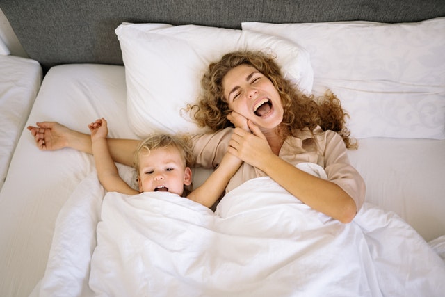 Sleeping on cotton sheets is a great option for all family members. Alt-tag. mother and son playing in bed.